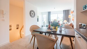 A modern dining area with wicker chairs, a dark wooden table, and a vase of flowers.