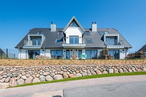 Ein modernes, zweistöckiges Haus mit einer Steinschmalseite, großen Fenstern und blauem Himmel.
