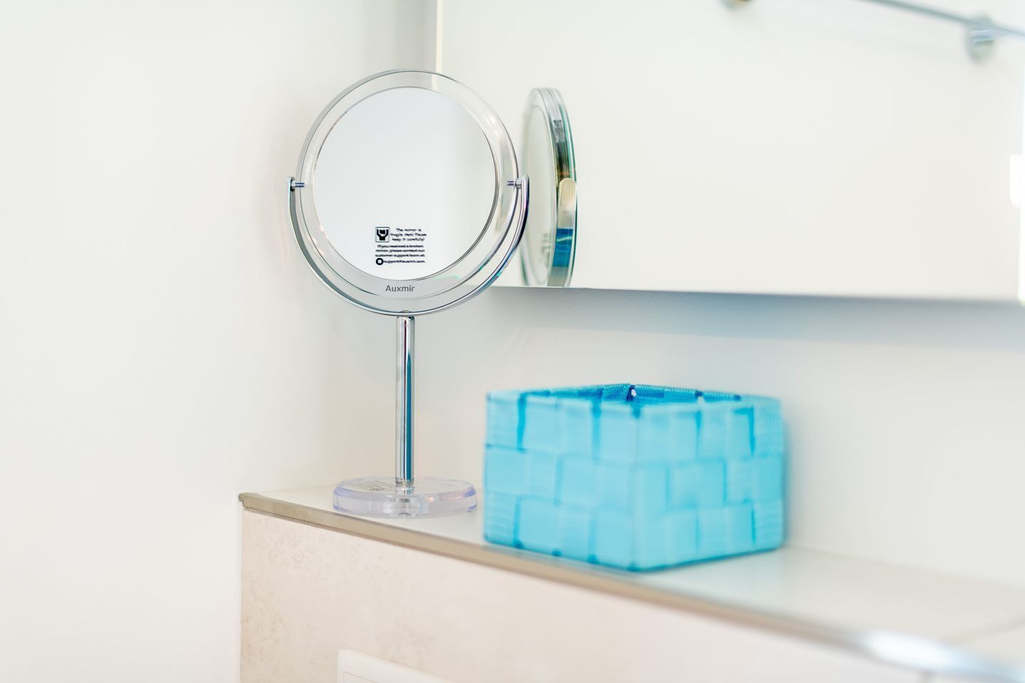 A bathroom vanity with a round mirror, a blue soap dispenser, and a cabinet above.