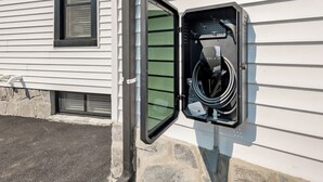 An electrical box with a hose attached to it, mounted on a building's exterior wall.
