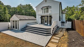 A two-story house with a balcony, a small attached garage, and a paved patio area.