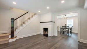 A spacious living area with a staircase, a fireplace, and a dining area.
