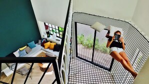 A person lying on a hammock chair in a room with a view of greenery outside. - Casa Búho & Casa Arco (Tulum)