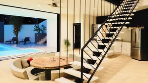 A modern interior with a spiral staircase, a pool view, and a dining area with a round table. - Casa Búho & Casa Arco (Tulum)