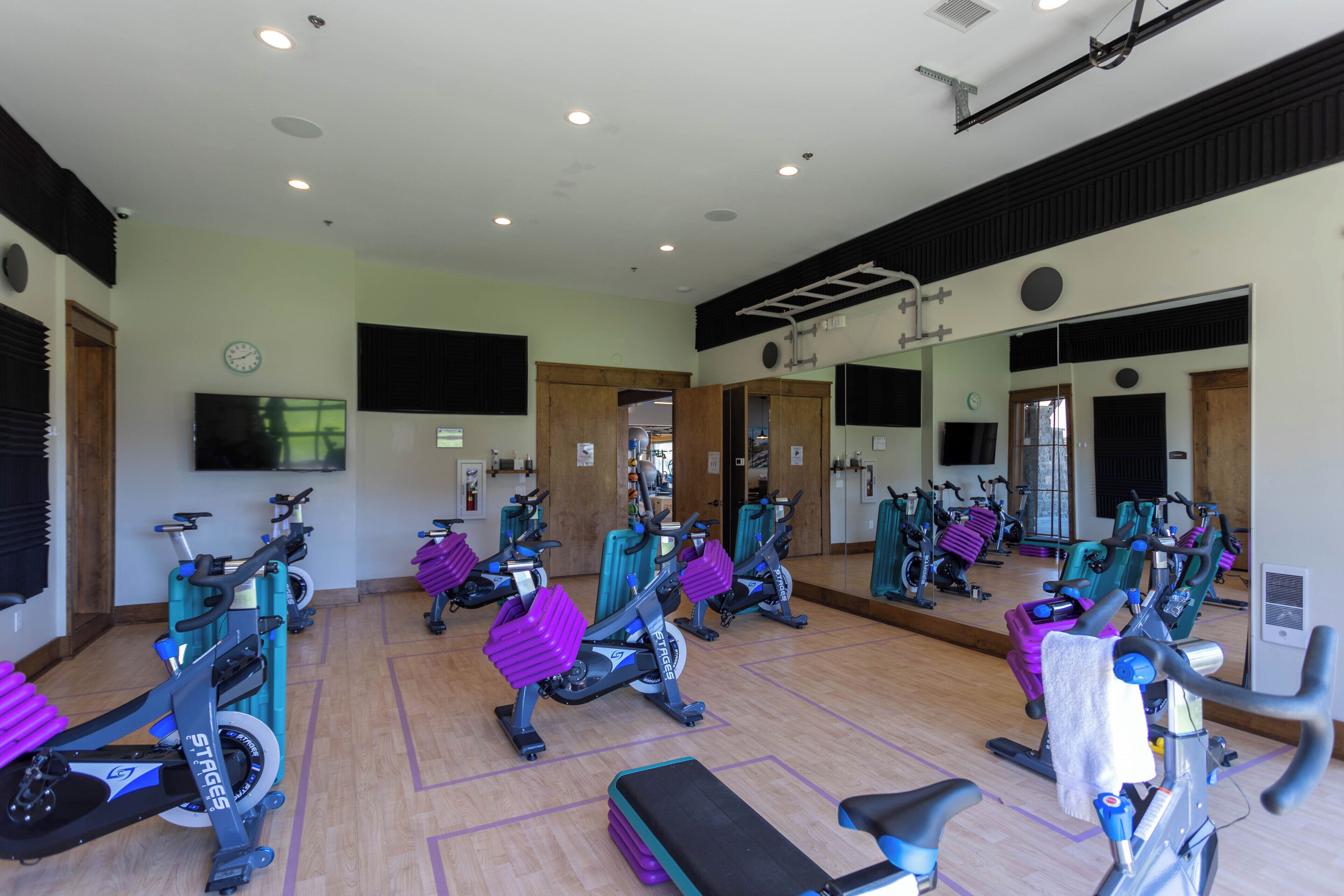 Une salle de sport équipée de plusieurs vélos d’exercice, d’un banc et de miroirs aux murs.