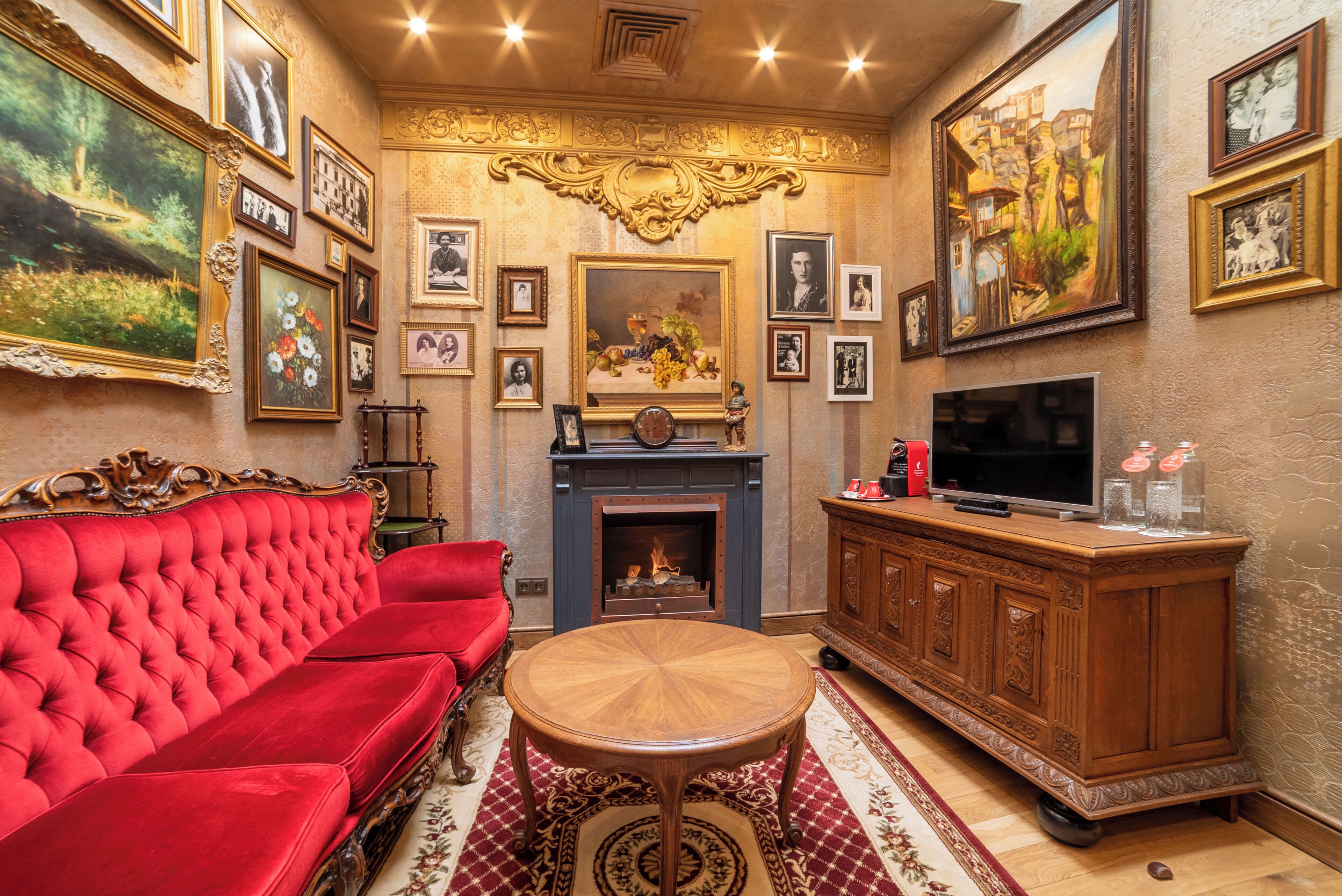Een woonkamer met een rode bank, een houten salontafel, een open haard en een televisie.