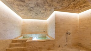 Een wellnessruimte met een marmeren vloer, een bad en een douche.