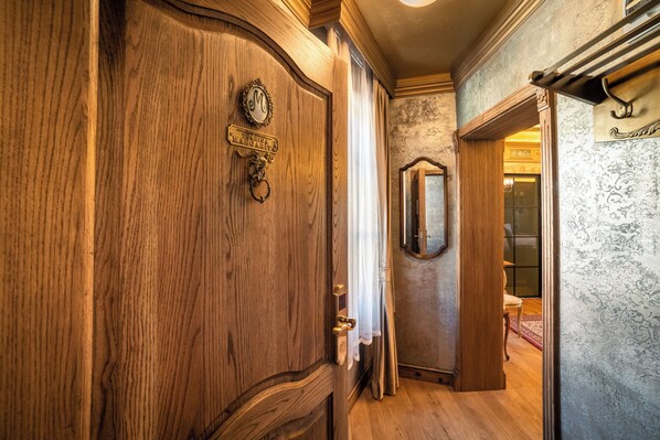 Una puerta de madera con un picaporte de latón y una placa, un espejo en la pared y un suelo de madera.