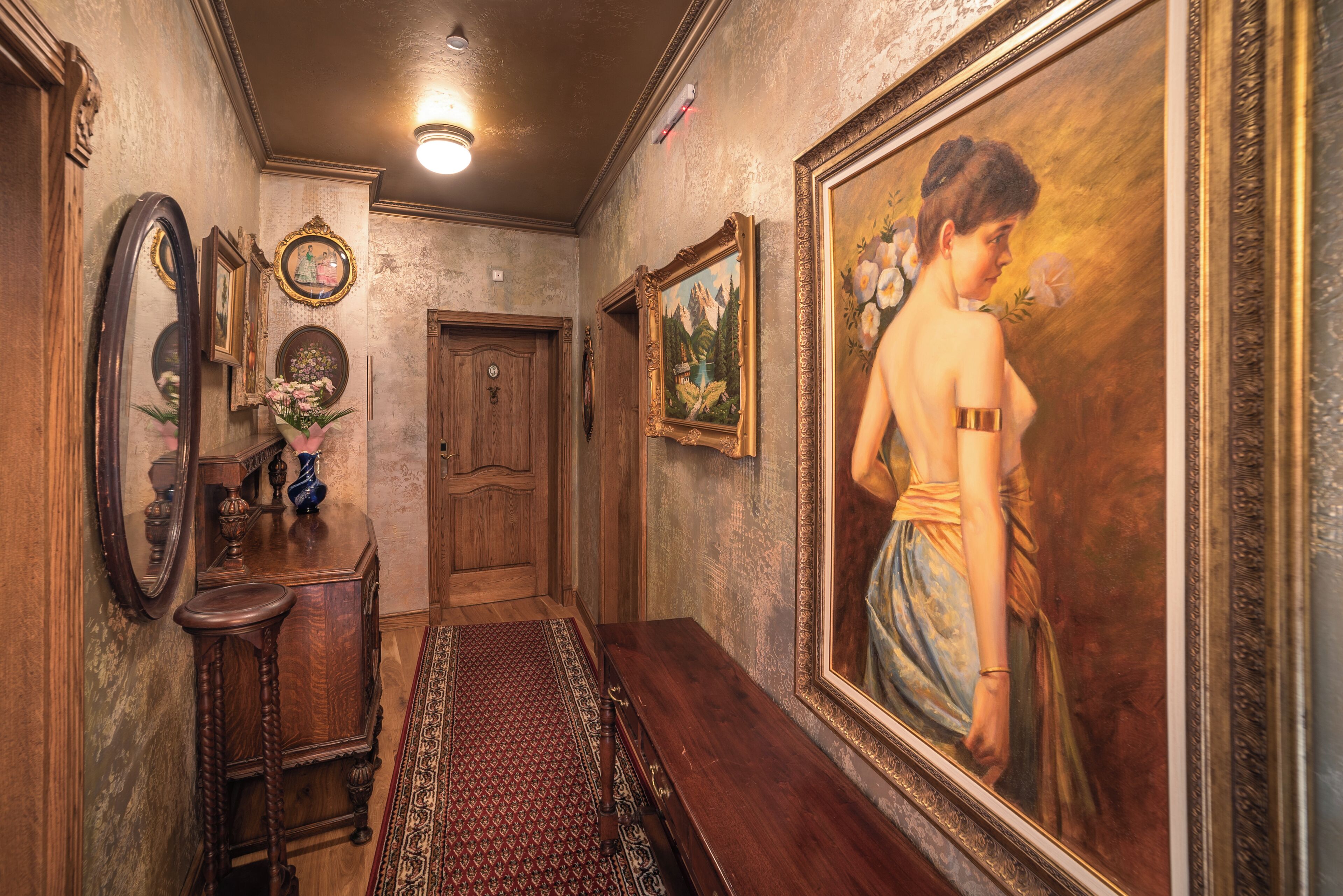A hallway with wooden furniture, a mirror, and framed artwork on the walls.
