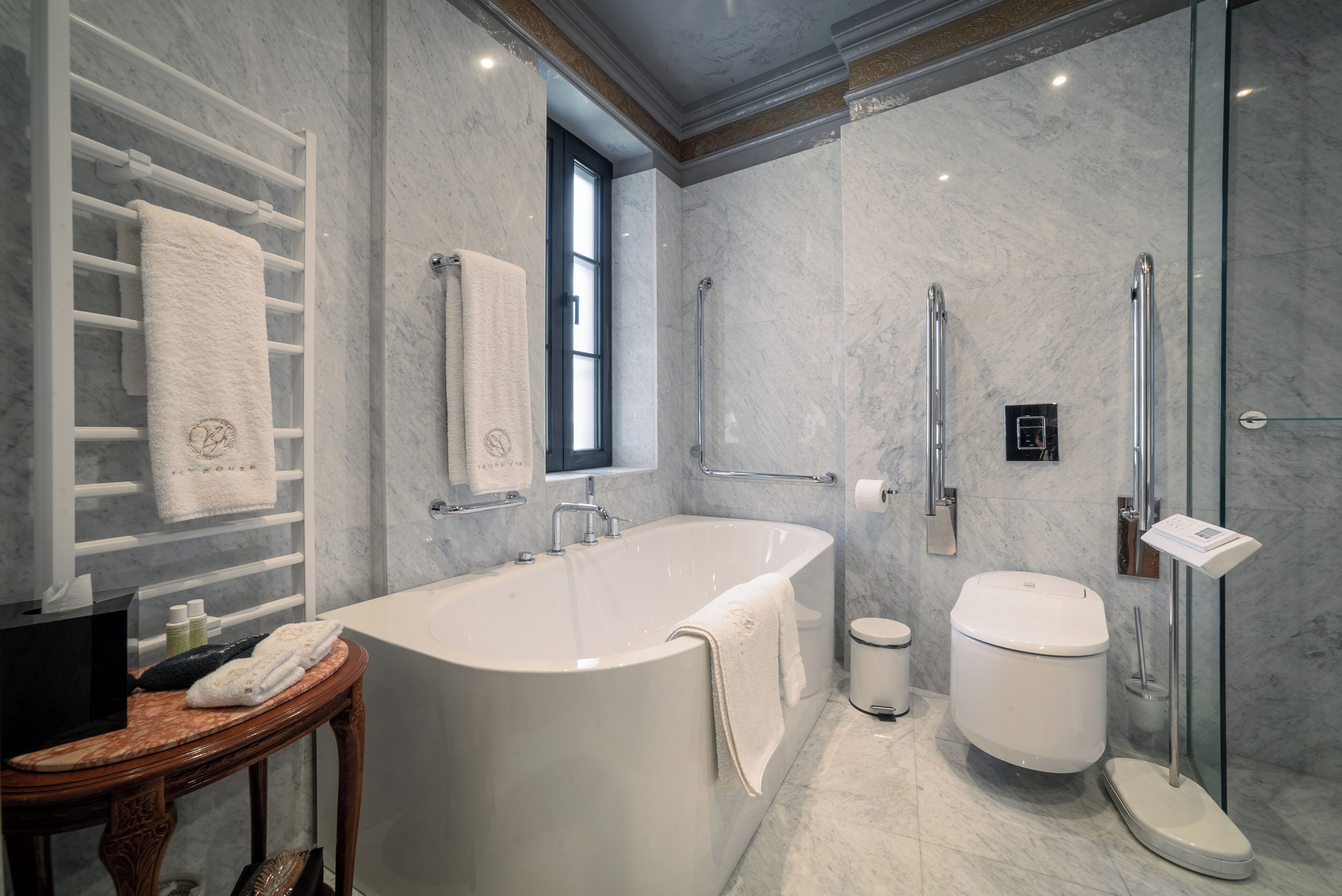 A modern bathroom with a freestanding bathtub, a glass-enclosed shower, a toilet, and a vanity with a towel rack.