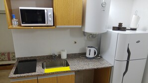 Cocina compacta con microondas, hervidor y refrigerador.
