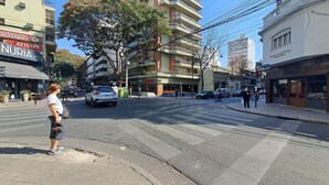 Vista de la calle con edificios, un paso de peatones y una persona de pie.