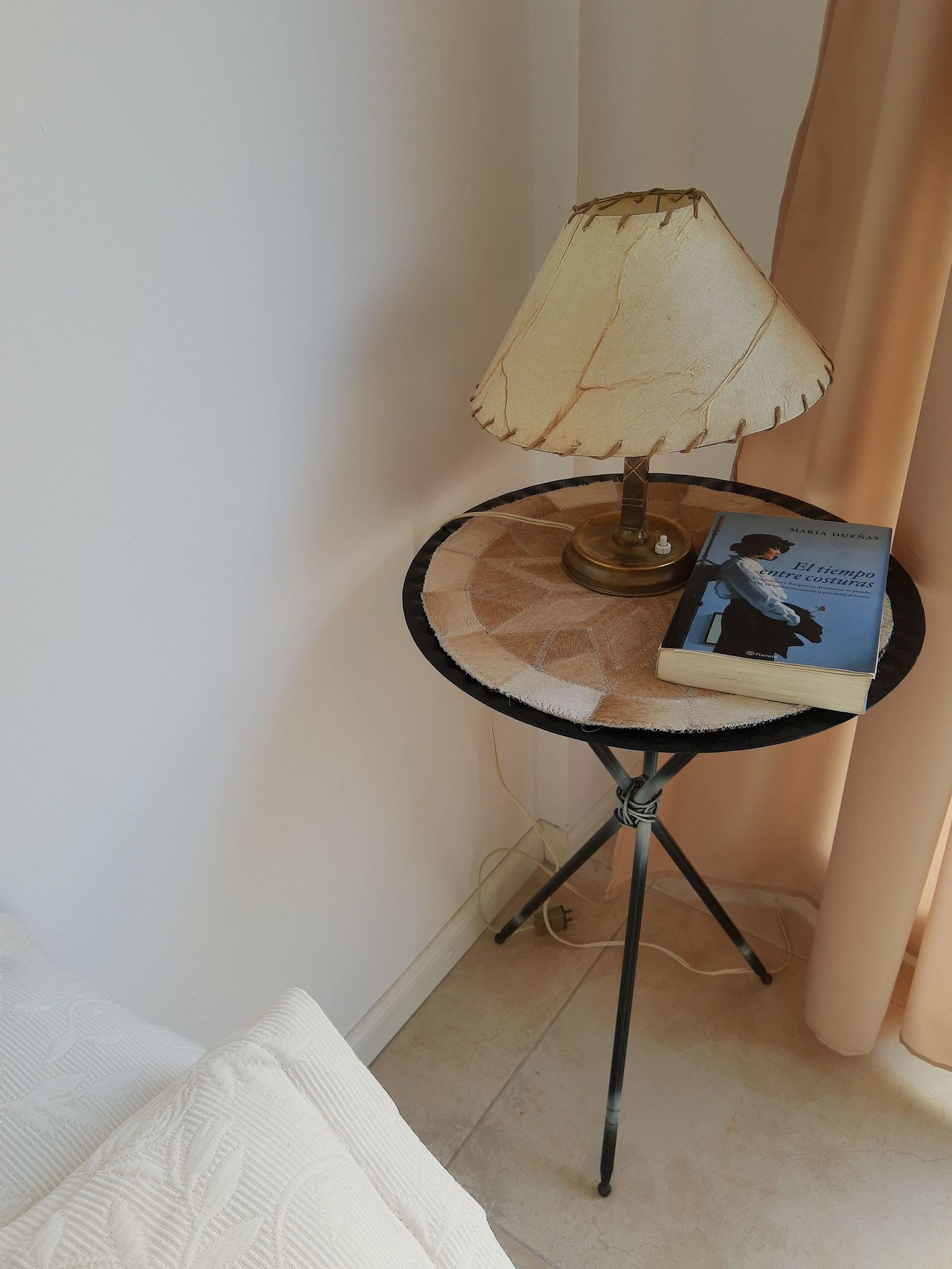 Une petite table ronde avec une lampe et un livre.