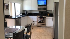 Een moderne keuken met witte kasten, een roestvrijstalen oven, een magnetron en een koelkast.