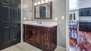 Un baño con tocador de madera oscura, un espejo grande y una lámpara colgante.