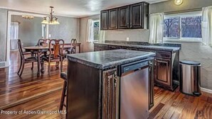 Una cocina con armarios de madera, encimera de granito y lavavajillas integrado.
