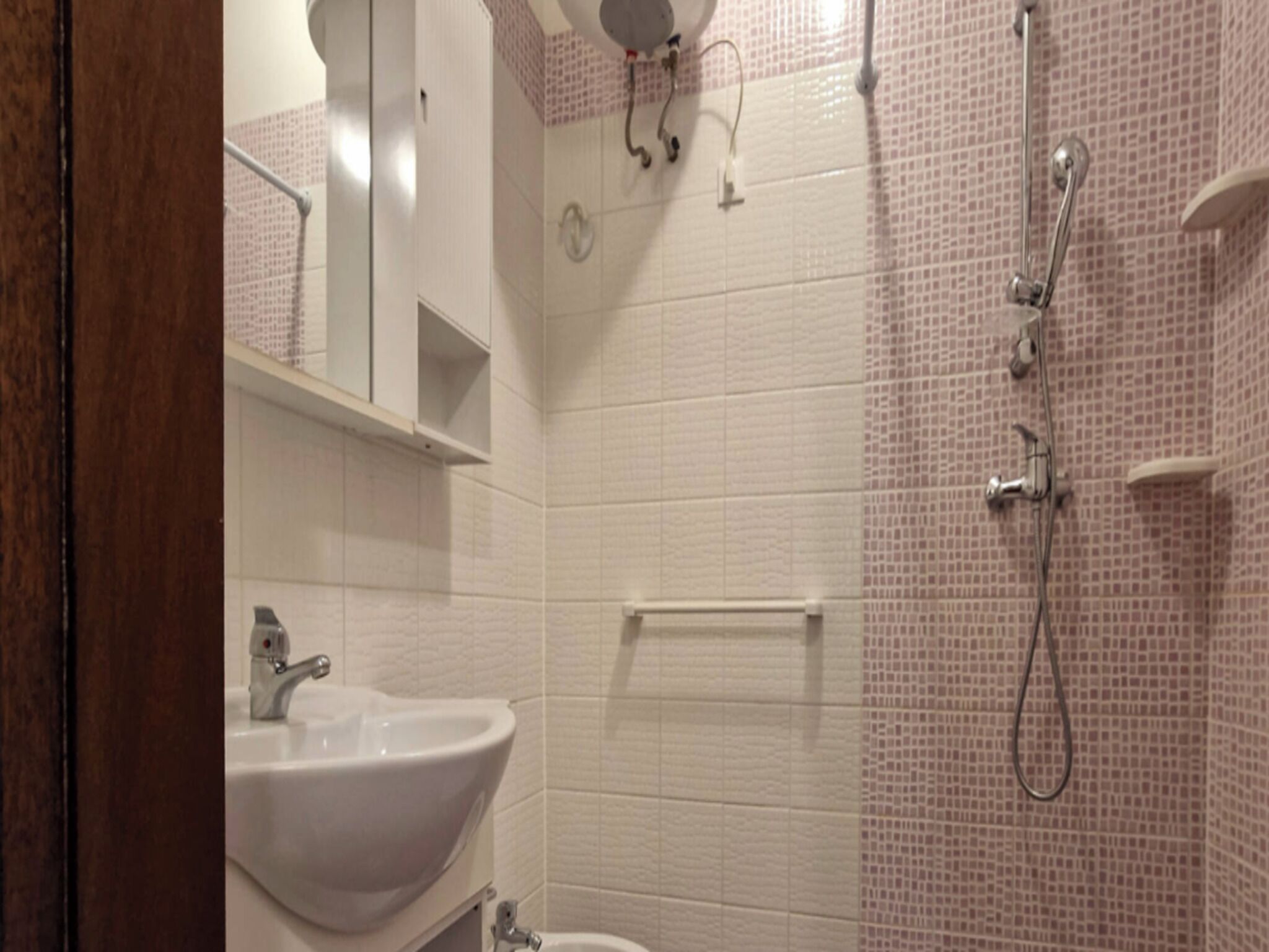 A bathroom with a white sink, a toilet, and a shower area with a tiled wall.