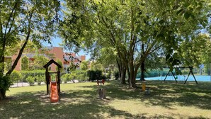 Un parc avec une balançoire, un toboggan et une petite structure en bois.