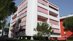A multi-story building with balconies, a flat roof, and a red and white color scheme. - Modern Flat for 6 Guests With Swimming Pool (San Michele al Tagliamento)