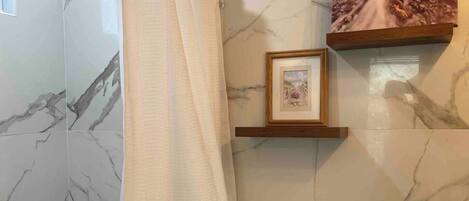 Uma casa de banho com cortina de chuveiro, sanita e um quadro emoldurado na parede.