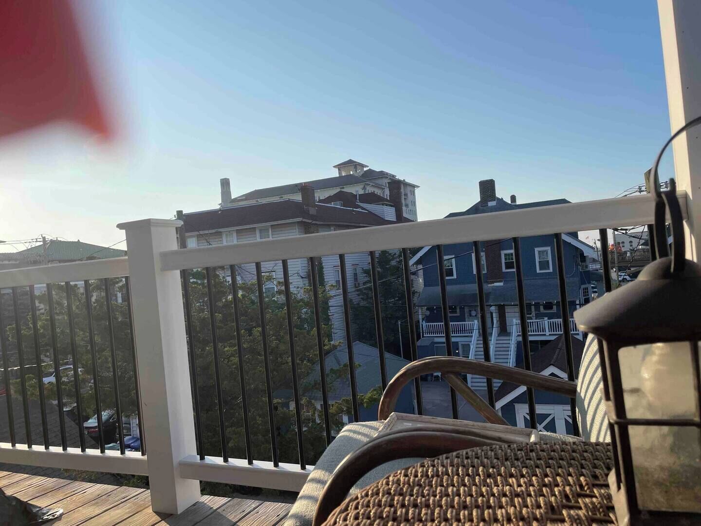 A balcony with a white railing, wicker furniture, and a view of neighboring houses.