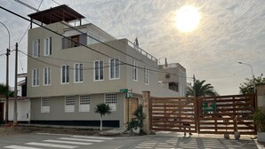 A multi-story residential building with a gated entrance, a crosswalk, and a street with vehicles. - Modern Beach Retreat with Pool- 5-Min Walk to Punta Hermosa’s Best Beach (San Miguel)