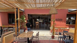 An outdoor seating area with wooden tables and chairs, a red brick floor, and a wooden pergola overhead. - Modern Beach Retreat with Pool- 5-Min Walk to Punta Hermosa’s Best Beach (San Miguel)
