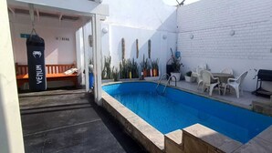 A swimming pool with a white brick wall, a bench, and outdoor furniture. - Modern Beach Retreat with Pool- 5-Min Walk to Punta Hermosa’s Best Beach (San Miguel)