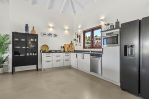 A modern kitchen with a black refrigerator, stainless steel appliances, white cabinetry, and decorative items on the wall.