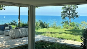 A modern room with large windows overlooking a grassy area and the sea.