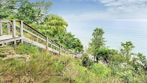 A wooden staircase leading down to a beach, surrounded by greenery and overlooking the sea.