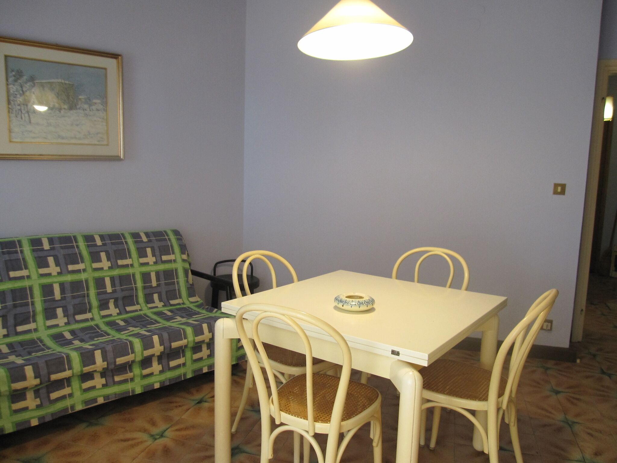 Un coin repas comprenant une table et quatre chaises, un canapé et un tableau encadré accroché au mur.