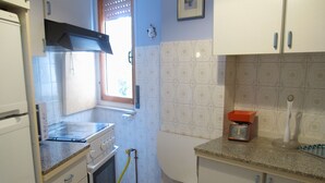 A compact kitchen with white cabinets, a stove, an oven, a window, and a sink.