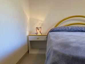 Ett sovrum med en säng, ett nattduksbord och en lampa.