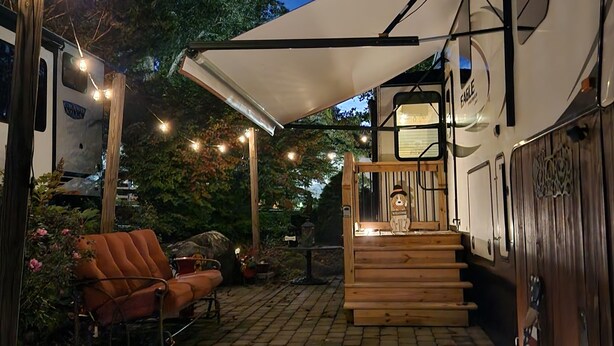 A covered outdoor area with a wooden bench, a dog statue, and a stone-paved floor.