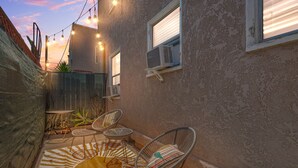 An outdoor patio with wicker chairs, a striped rug, and string lights. - Minutes from Beach - No Cleaning Fee - Free Parking - FIFA 2026! (Long Beach)