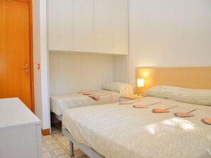 A bedroom with two beds, a wardrobe, and a bedside table with a lamp.