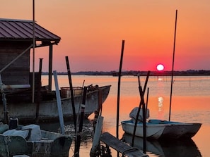 A sunset over a calm body of water with boats docked at a pier. - Modern Apartment With two Balconies (Rosolina)