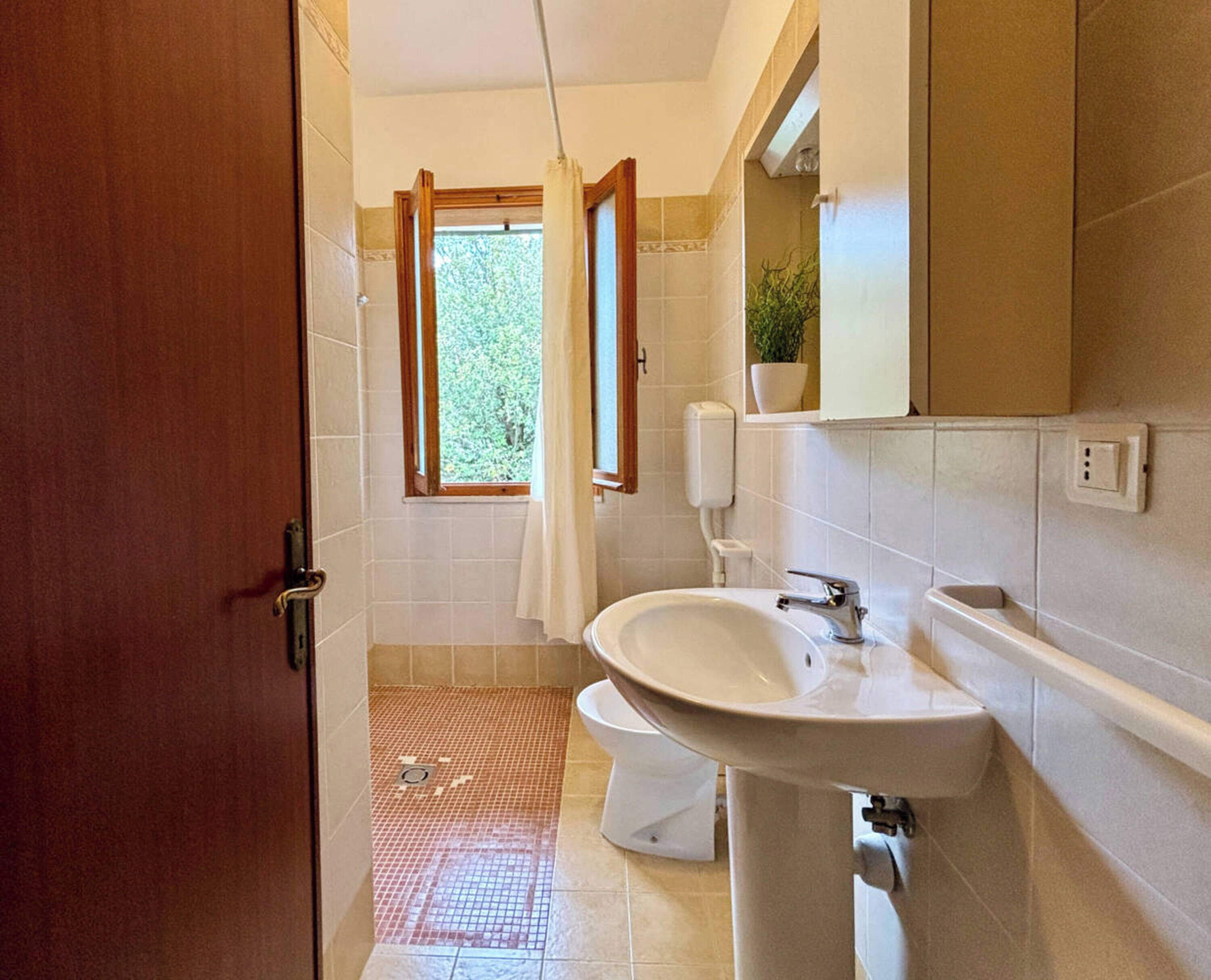 Une salle de bain avec un lavabo, des toilettes et une fenêtre avec des rideaux.