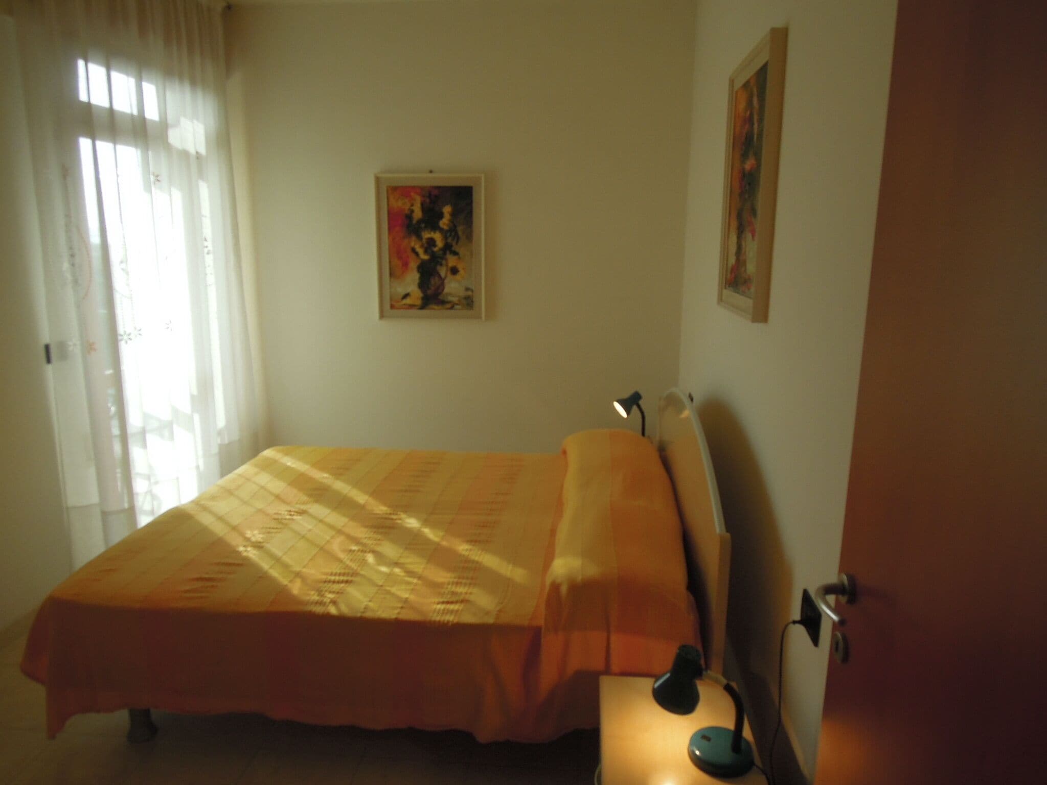 Een slaapkamer met een bed, een bedlamp en een schilderij aan de muur.