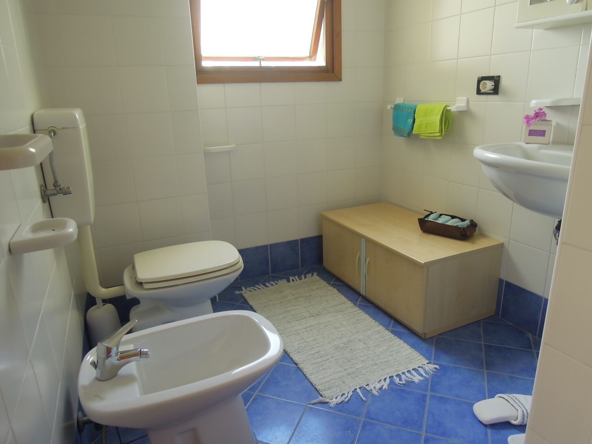 A compact bathroom with a toilet, sink, and a small cabinet.