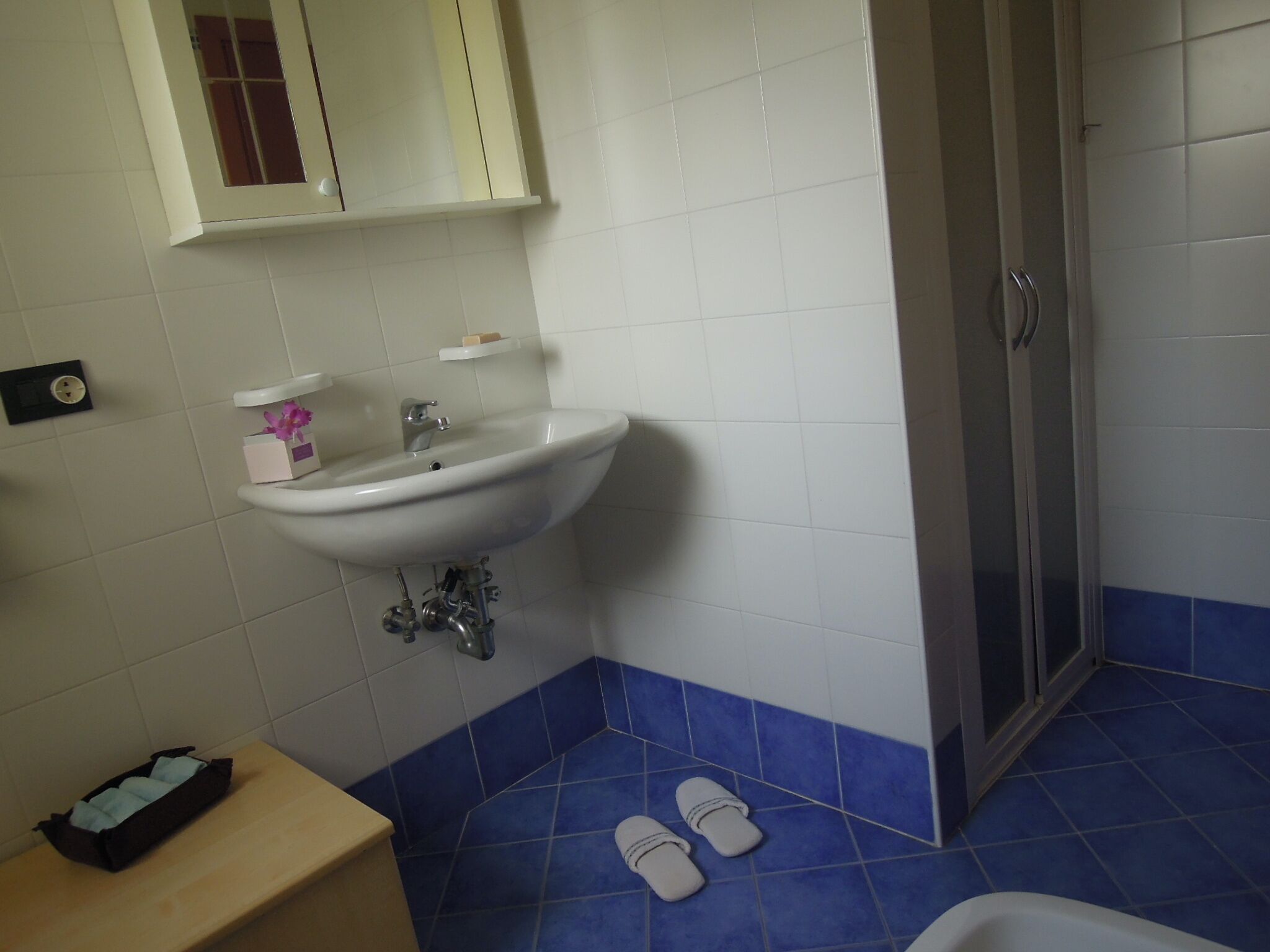 Ein Badezimmer mit Waschbecken, Spiegel und blau gefliestem Boden.