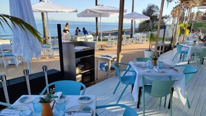 Un espace extérieur aménagé pour les repas, avec des tables et des chaises, offrant une vue sur la plage.