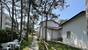 A pathway leading to a building with outdoor seating and a barbecue area. - Cozy Villa With Private Garden (San Michele al Tagliamento)