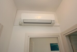 Un equipo de aire acondicionado blanco montado en una pared sobre una puerta.