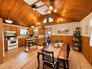 A spacious kitchen with wooden cabinets, a dining area with a table and chairs, and a ceiling fan.