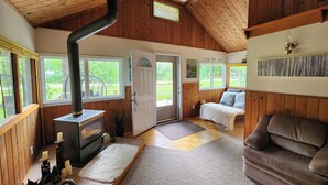 Ein gemütliches Blockhaus-Interieur mit Holzbalkendecke, Kamin, einer Couch und einem Essbereich.
