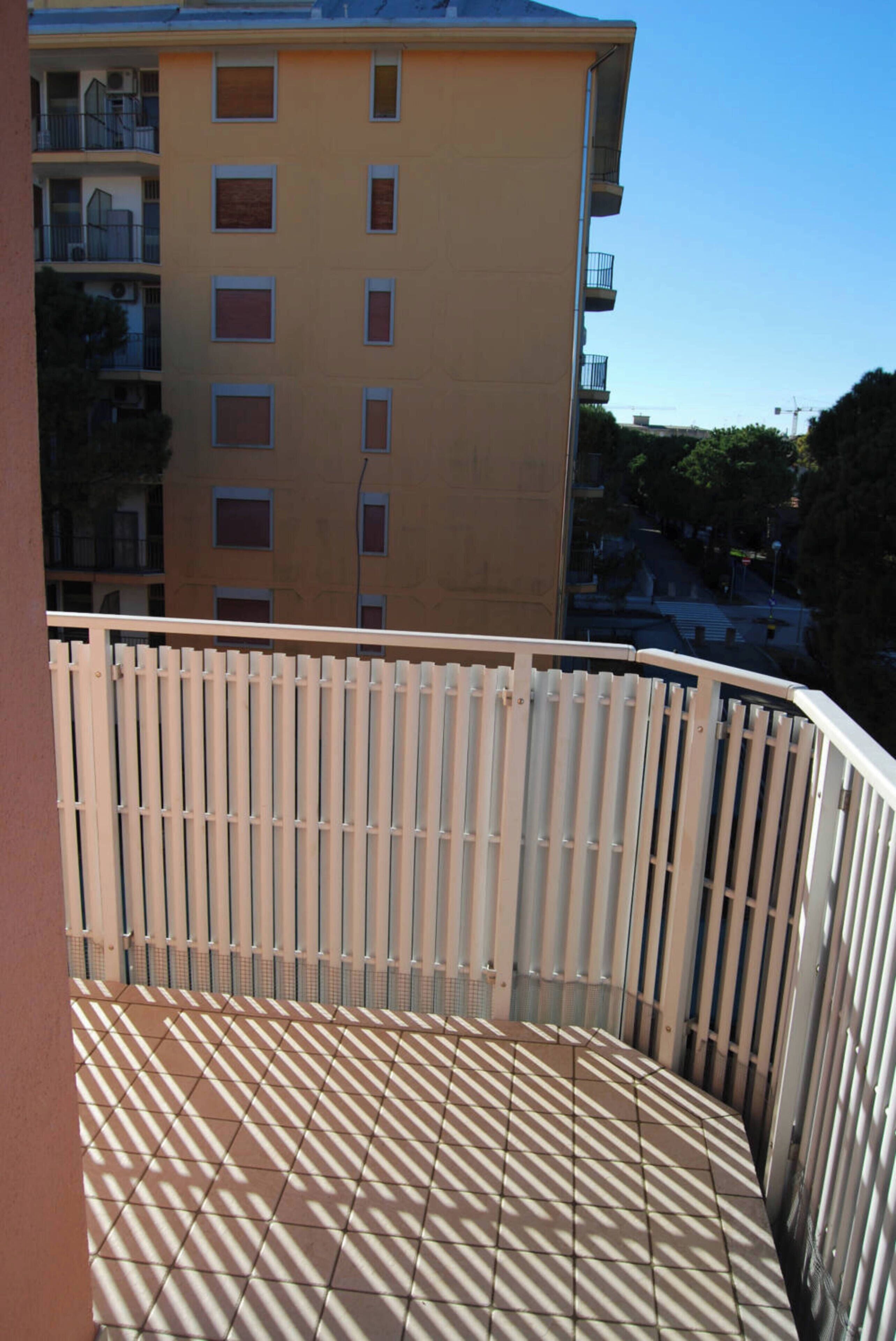 A balcony with a tiled floor and a white railing.