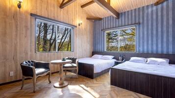 A modern hotel room with large windows, a wooden floor, and a bed with two pillows.