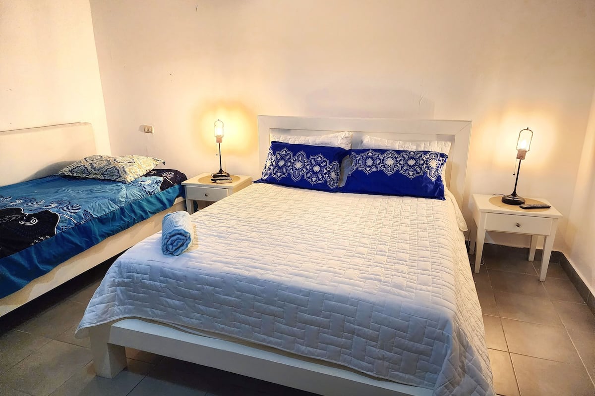 A bedroom with two beds, each with a bedside table and lamp.
